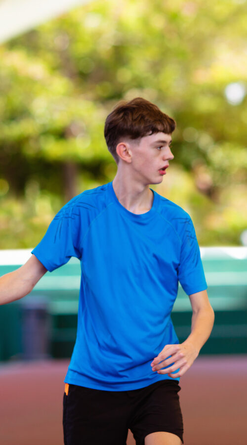Young man playing tennis on open court. Teenager with racquet at competition match. Healthy outdoor sport for high school or college kids. Student exercising.
