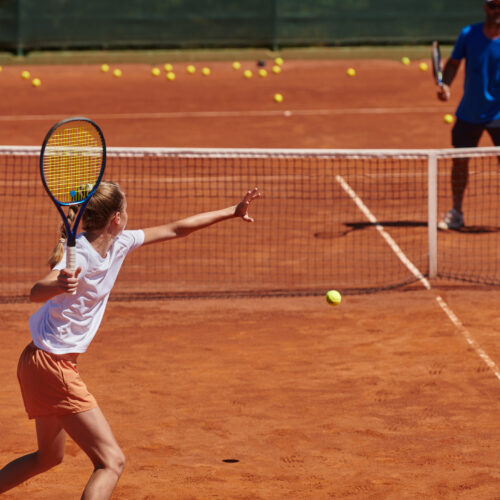 A professional tennis player and her coach training on a sunny day at the tennis court. Training and preparation of a professional tennis player.