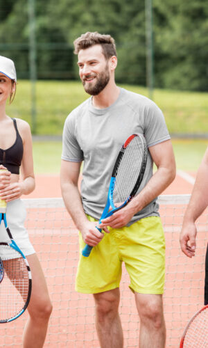 Group of friends having fun standing together with rackets on the tennis court