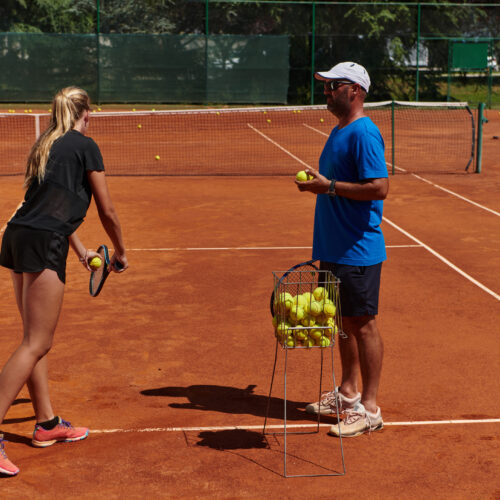 A professional tennis player and her coach training on a sunny day at the tennis court. Training and preparation of a professional tennis player.